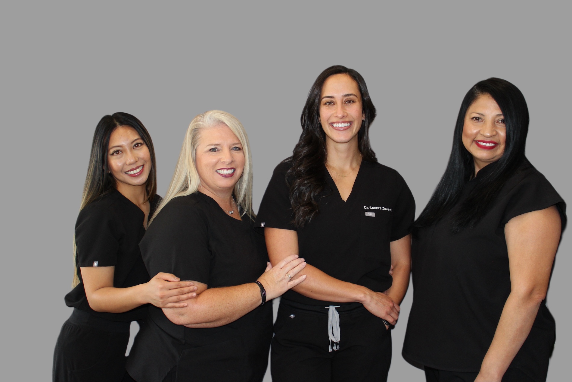 Alt text   A group of five women in scrubs posing for a photo with smiles.
