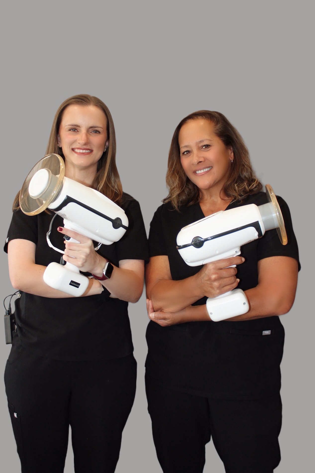 Two individuals posing with a surveillance camera, one holding a device resembling a microphone or speaker, against a neutral background.