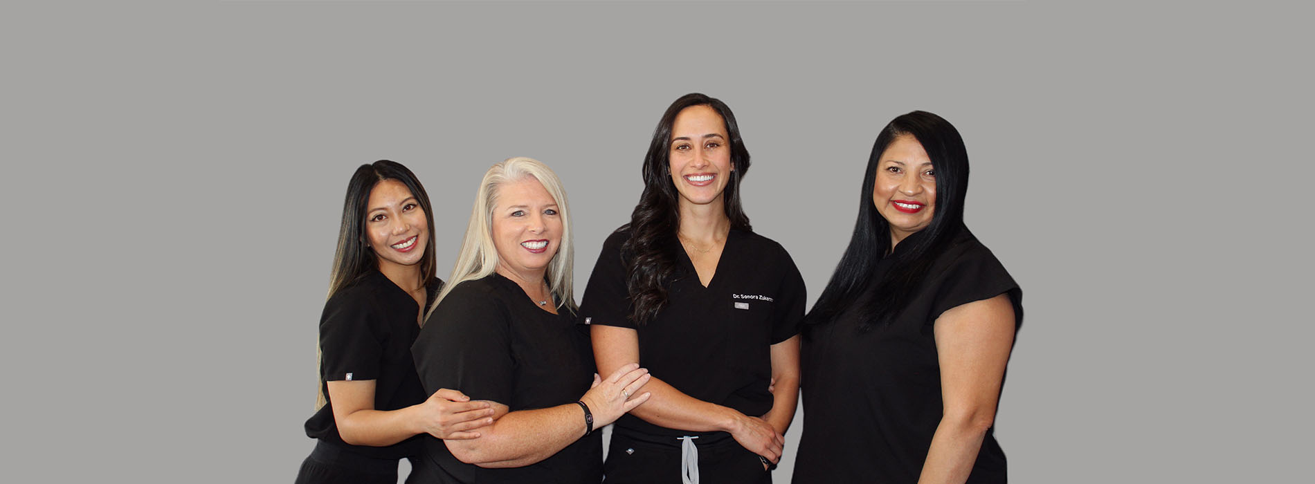 The image shows a group of five individuals, likely professionals given their attire, posing together for a photograph with smiles on their faces.