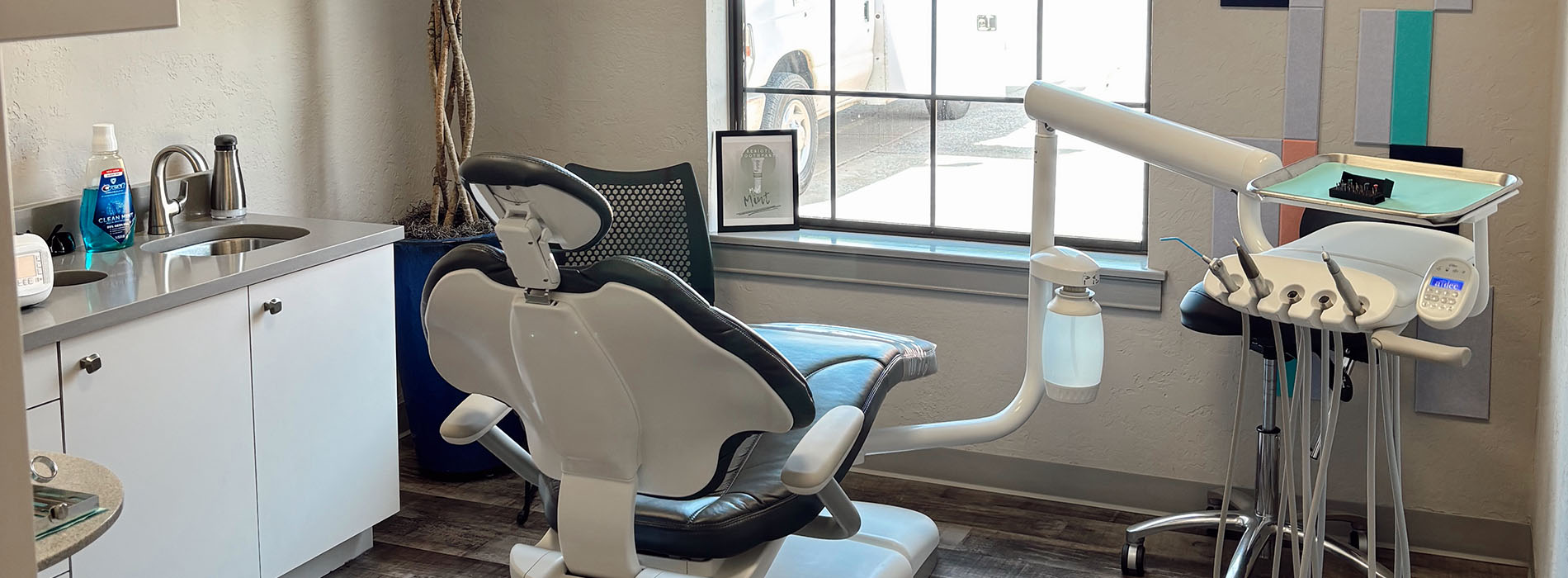 The image shows a modern dental clinic interior with various pieces of equipment, including a dental chair and an X-ray machine.