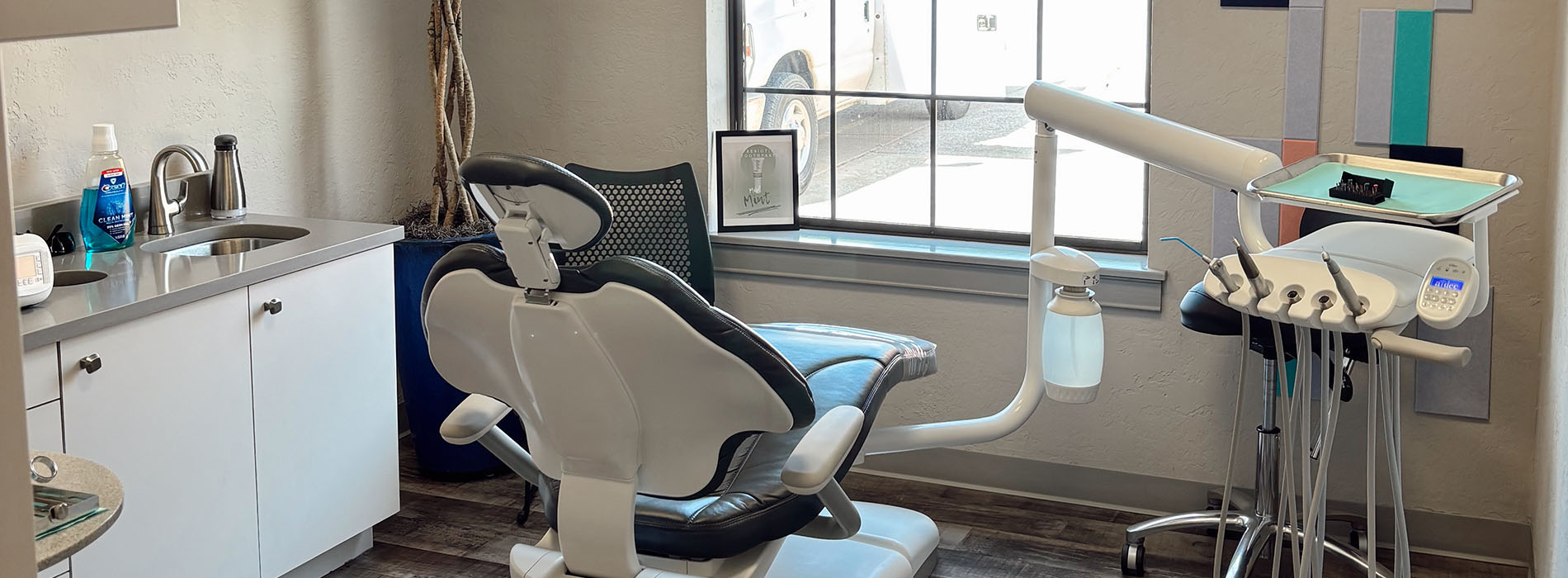 The image shows an interior view of a dental office, featuring a reception area with a modern desk and chair, dental equipment on display, and a clean, well-lit environment.
