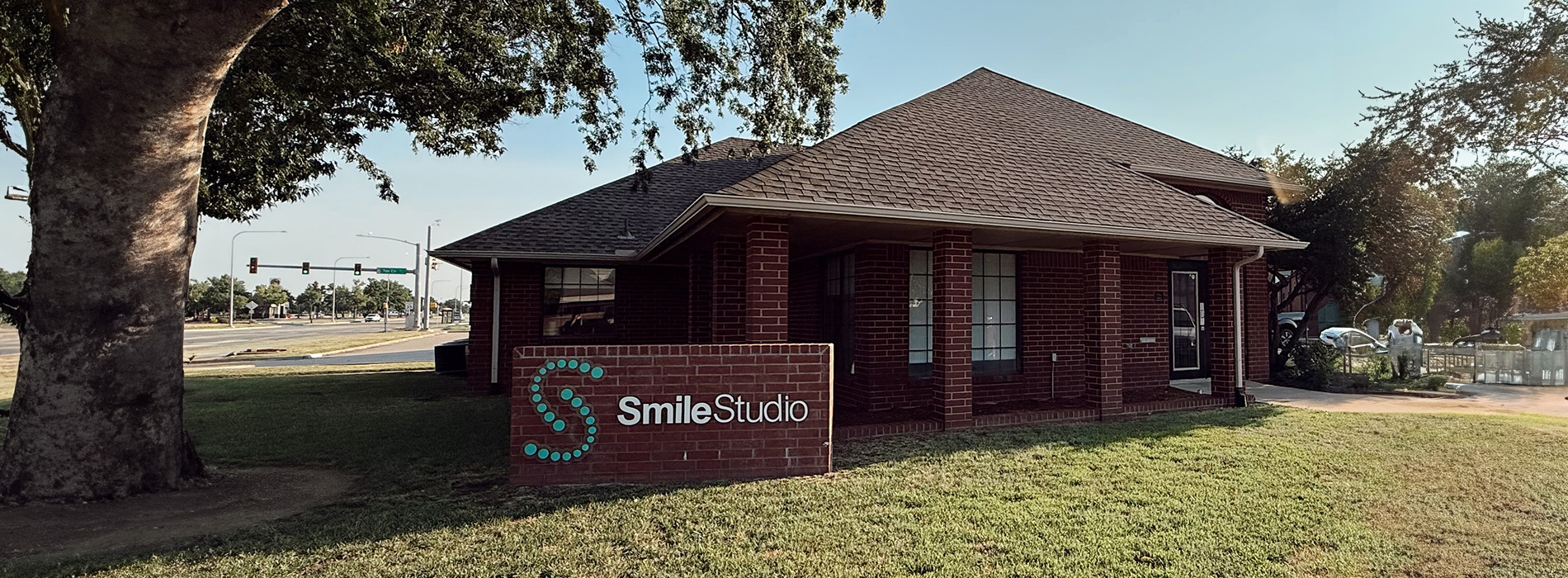 The image shows a building with a sign that reads  SMILE SHOOTS,  indicating it s a dental clinic, set against a clear sky during daylight.