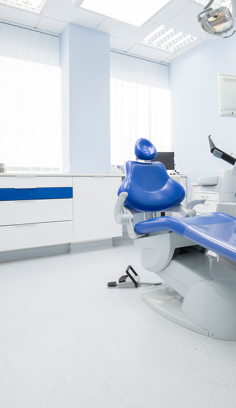 The image shows a modern dental or medical office interior with a dental chair, equipment, and a clean, professional environment.