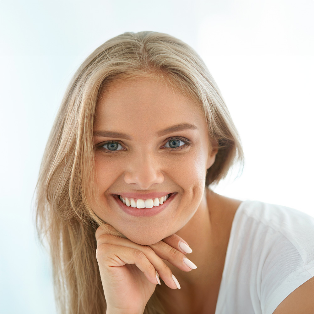 The image features a woman with blonde hair smiling at the camera, with her hand resting on her chin.