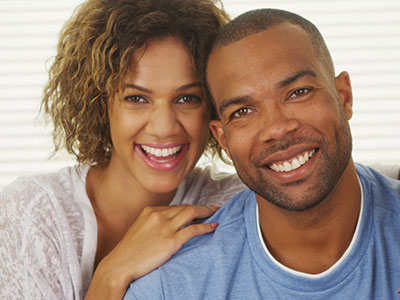 The image shows a man and woman posing together with smiles on their faces  they appear to be a happy couple sharing a joyful moment.