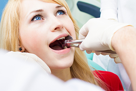 A woman receiving dental care with a dentist performing an examination using specialized equipment.